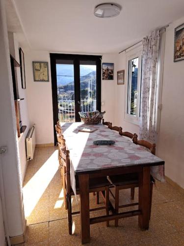 d'une salle à manger avec une table, des chaises et une fenêtre. dans l'établissement Aux romarins, à Reynès