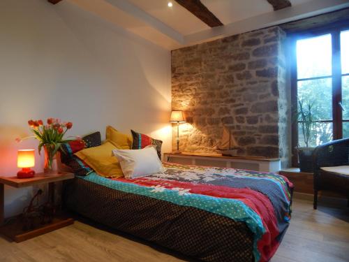 een slaapkamer met een bed met een stenen muur bij Hauts De La Brancherie in Léhon