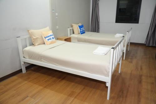 two white beds in a room with wooden floors at Bkk39 Airport hotel in Ban Khlong Prawet