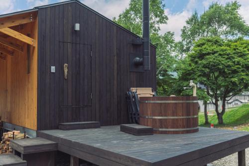 a wooden building with a bench and a wooden barrel at Earthboat Togakushi in Nagano