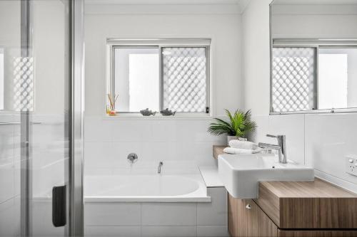 a white bathroom with a sink and a shower at 36 Petrie Avenue in Marcoola