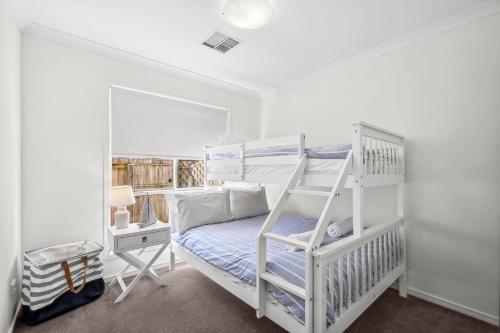 a white bedroom with a bunk bed and a ladder at 36 Petrie Avenue in Marcoola