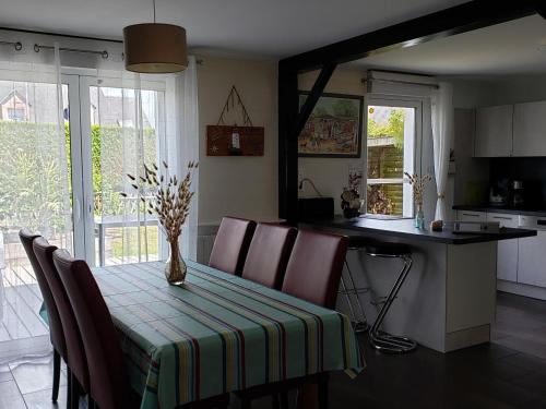 une cuisine avec une table avec un vase de fleurs dessus dans l'établissement Maison cosy à Guérande, proche cité médiévale, avec jardin, terrasse, fibre et home cinéma. - FR-1-306-970, à Guérande