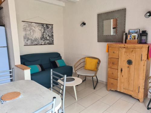 un salon avec un canapé bleu et une table dans l'établissement Maison rénovée avec jardin partagé de 2000m² à 1,3 km de la plage Clemenceau, idéale pour 4 personnes - FR-1-426-510, à Saint-Vincent-sur-Jard