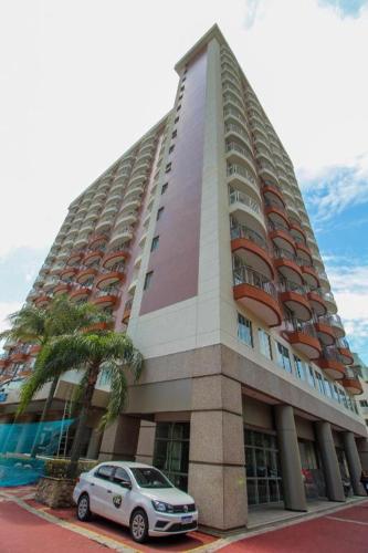 a car parked in front of a tall building at Barra da Tijuca - 508 - De Frente para Maravilhosa Piscina - Estacionamento Gratuito - Academia Comphania Atletica - Balsa para Praia Grátis - Microondas - Geladeira Grande - Recepção 24horas - Wi-Fi - Com Pia in Barra da Tijuca