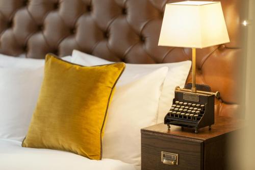 a lamp on a table next to a bed with an old typewriter at Hotel Indigo - Edinburgh - Princes Street by IHG in Edinburgh