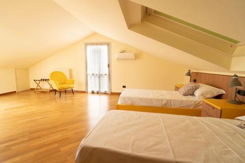 a attic bedroom with two beds and a yellow chair at Belvedere a Monte in Rovagnate