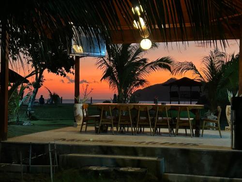 a table and chairs with a sunset in the background at Mama Nings Beach Hotel in Sekongkang