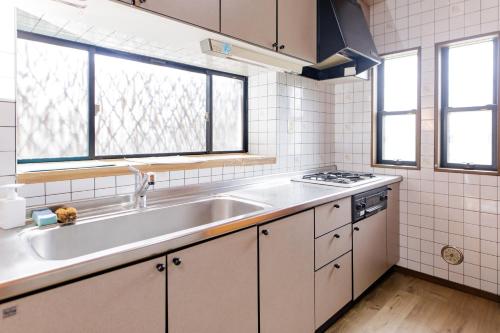 a white kitchen with a sink and a stove at ocean resort mint オーシャンビューを満喫!かわいい三角屋根の三階建て貸切別荘 南房総白浜 in Shioura