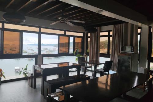 een eetkamer met een tafel, stoelen en ramen bij A Place To Remember El Nido Palawan in El Nido