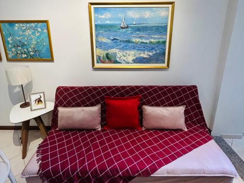 a couch with two pillows in a room with a painting at Apartamento Beira Mar Praia da Costa in Vila Velha