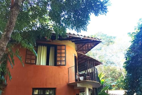 an orange building with a balcony and a tree at Casa Sustentável de Terra! in Lençóis