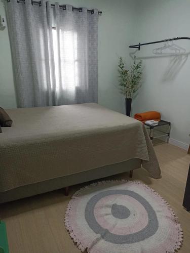 a bedroom with a bed and a window with a rug at Quarto 1 para mulher in Maringá