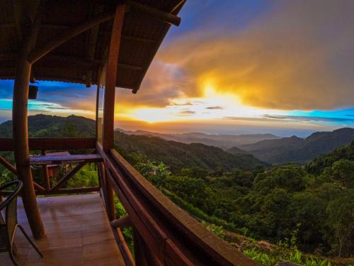 a view from the balcony of a mountain house with a sunset at Loma Nevada Minca Hotel in Minca