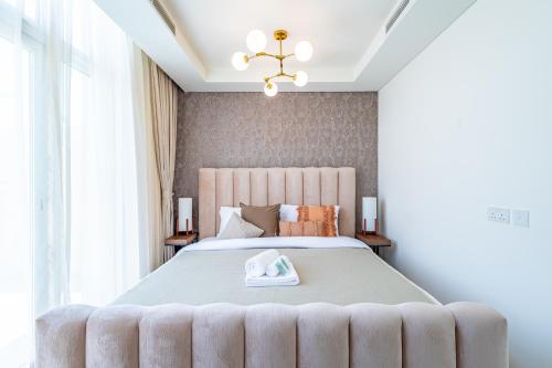 a bedroom with a large bed and a chandelier at Luxury 3BR 2storey Villa with Garden in Damac Hills in Dubai