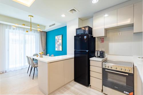 a kitchen with a black refrigerator and a table at Luxury 3BR 2storey Villa with Garden in Damac Hills in Dubai