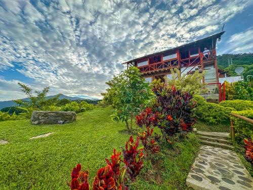 米卡Loma Nevada Minca Hotel的山丘上一座房子,前面有鲜花
