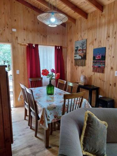 a dining room with a table with a vase of flowers on it at Marbella in Caburgua