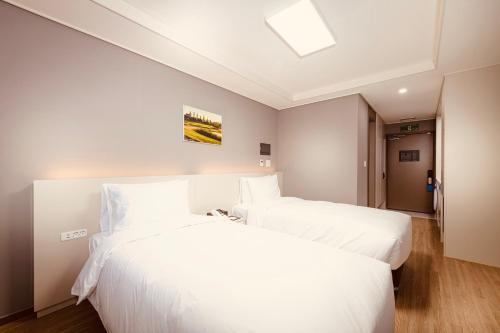 two beds in a hotel room with white sheets at Sollago Myeongdong Hotel & Residence in Seoul