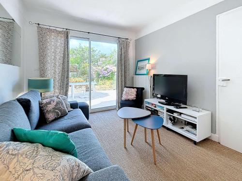 un salon avec un canapé bleu et une télévision dans l'établissement Jolie maison à 400m de la plage, proche centre-ville, avec terrasse et wifi gratuit - FR-1-361-55, à Donville-les-Bains