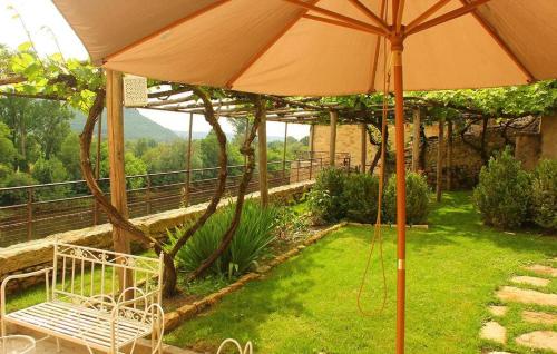 un patio avec un parasol et un banc dans l'herbe dans l'établissement Maison O'Galop, à Beynac-et-Cazenac