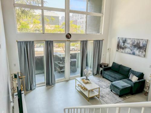 a living room with a green couch and large windows at Beautiful Loft in Little Italy SD with Parking in San Diego