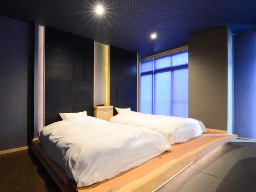 a bedroom with a large white bed with a window at 日本旅館 器 別府鉄輪 nihonryokan utsuwa beppukannnawa in Beppu