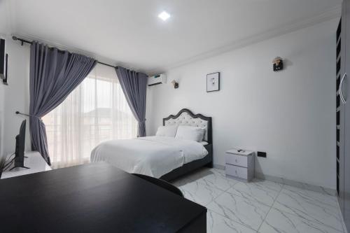 a white bedroom with a bed and a window at Spacious 3 bed - Fast Internet - Free Parking - Swimming Pool in Lagos