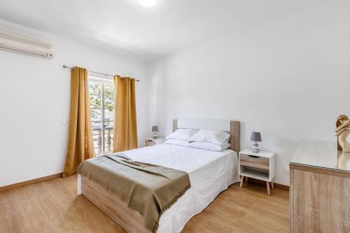 a white bedroom with a bed and a window at Diamond & Pearl in Olhão