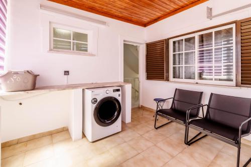 a laundry room with a washing machine and two chairs at Diamond & Pearl in Olhão