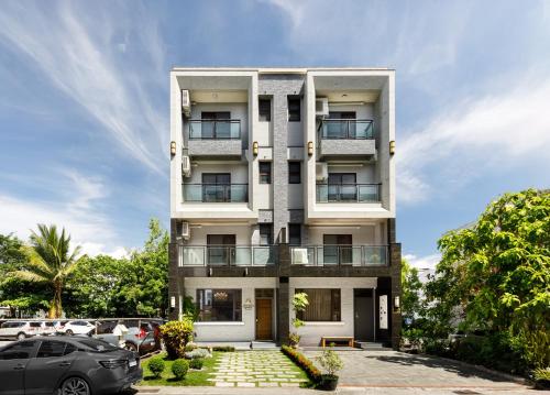 a white building with cars parked in a parking lot at When Happiness Knock your Door in Hualien City