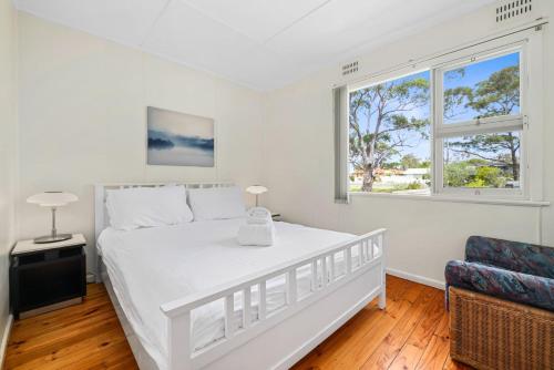 a white bedroom with a bed and a window at On Collingwood Beach by Book Jervis Bay - ON THE Bikepath TO Husky in Vincentia