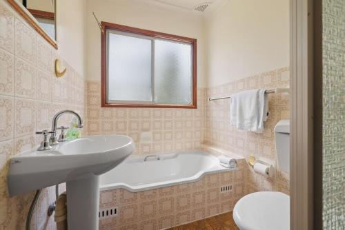 une salle de bain avec une baignoire, un lavabo et des toilettes dans l'établissement On Collingwood Beach - Upstairs Apartment, à Vincentia