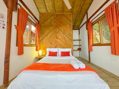 a bedroom with a large bed with red pillows at Loma Nevada Minca Hotel in Minca
