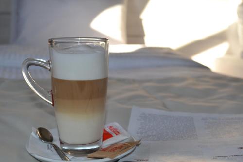 a glass mug of milk on a plate with a spoon at YMY HOTELS Târgu Jiu in Târgu Jiu