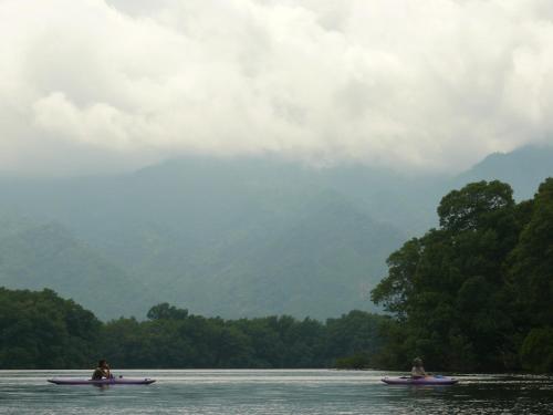 two people in canoes on a lake with trees at Omega Tours Eco-Jungle Lodge in La Ceiba