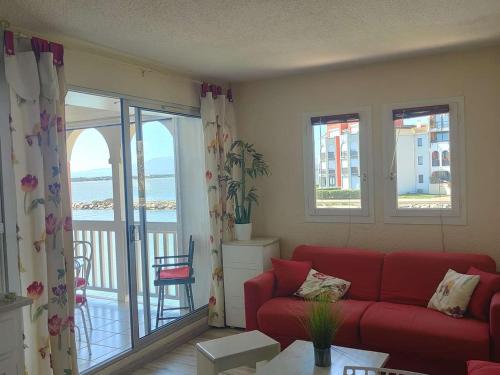 un salon avec un canapé rouge et un balcon dans l'établissement Appartement T2 - 4 pers. avec terrasse et piscine à Le Barcarès - FR-1-195-108, au Barcarès