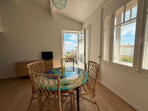 une salle à manger avec une table, des chaises et des fenêtres dans l'établissement Appartement cosy pour 4 pers, Royan, parking - FR-1-494-196, à Royan