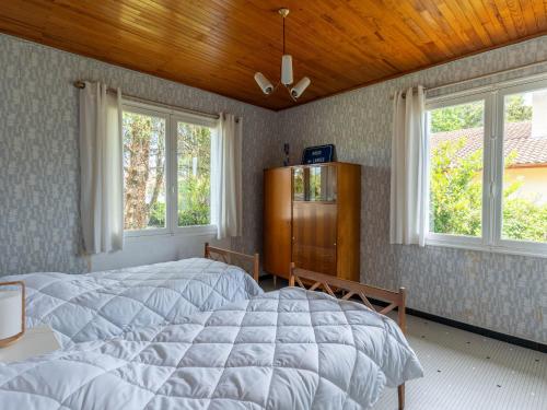 une chambre avec un grand lit et deux fenêtres dans l'établissement Maison de vacances près du lac d’Aureilhan à 3 km de Mimizan, pour 6 pers. avec grand jardin clôturé - FR-1-50-139, à Aureilhan