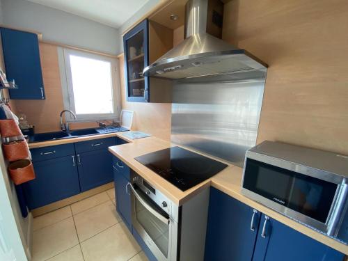 La cuisine est équipée de placards bleus et d'un four avec plaques de cuisson. dans l'établissement Appartement cosy face mer, avec terrasse et parking - Saint-Jean-de-Monts, secteur Casino - FR-1-323-550, à Saint-Jean-de-Monts