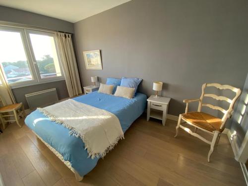 - une chambre avec un lit bleu et une chaise dans l'établissement Appartement cosy face mer, avec terrasse et parking - Saint-Jean-de-Monts, secteur Casino - FR-1-323-550, à Saint-Jean-de-Monts