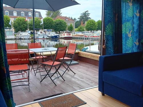 a patio with a table and chairs next to a marina at Séjour unique sur bateau grand confort à Digoin, 6 pers, terrasse, cuisine équipée - API-1-46-26 in Digoin