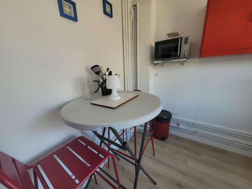 une petite table blanche avec deux chaises et un four micro-ondes dans l'établissement Charmant T2 de 20m² face à la plage de Berck-sur-Mer, avec chambre et ascenseur - FR-1-674-48, à Berck-sur-Mer