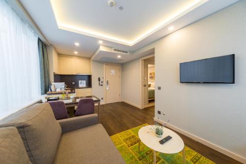 uma sala de estar com um sofá e uma televisão de ecrã plano em Molton Monapart Mecidiyekoy em Istambul