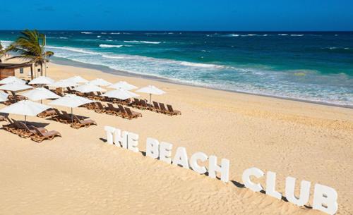 a beach with chairs and umbrellas and the words we beach club at Hard Rock Punta Cana Coral Bay II apartment 2 BR by BTC Crypto Group in Punta Cana