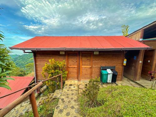 a small wooden house with a red roof at Loma Nevada Minca Hotel in Minca