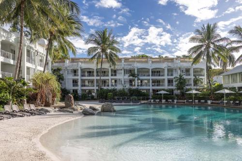 a resort with a swimming pool and palm trees at Peppers Beach Club & Spa in Palm Cove