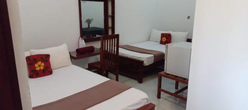 a room with two beds and a chair in it at Bee and Birds Hotel in Polonnaruwa