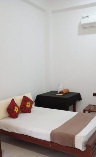 a bedroom with a bed and a table with a phone at Bee and Birds Hotel in Polonnaruwa