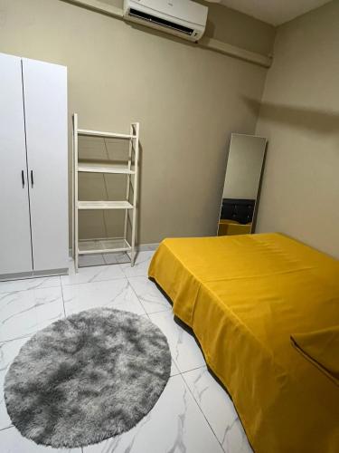 a room with a bed and a yellow blanket and a rug at Al-Hijrah Homestay Meru Klang in Kapar